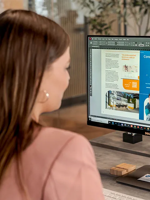 Eine Designerin arbeitet auf ihrem Bildschirm am Layout einer Broschüre.