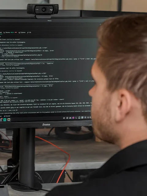 Ein Entwickler, von hinten gesehen, mit Code und einem Terminal auf dem Bildschirm.